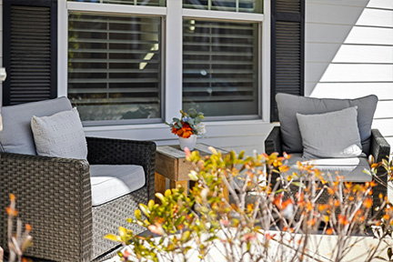 Two outdoor patio chairs in front of a window with shutters