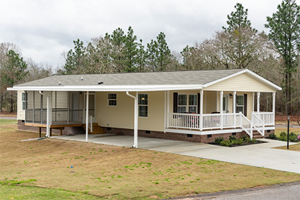Manufactured home with a driveway and carport made from an extension of the roof