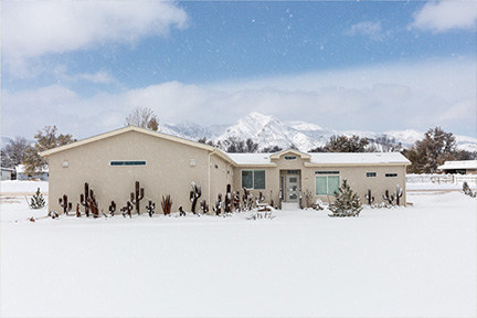 Manufactured home with Southwest lawn decor during a snow shower