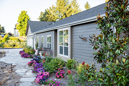 Front walkway of a manufactured home with flowers and bushes
