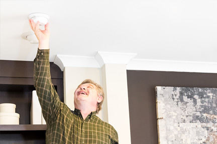 Man reaching up to adjust a lighting fixture on the ceiling